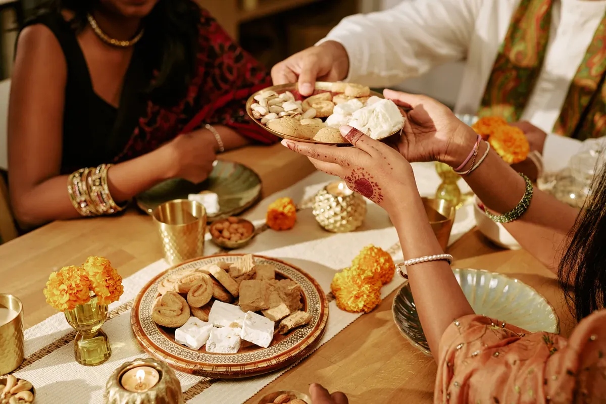 Hands sharing traditional sweets during a festive gathering