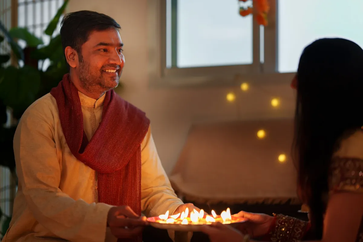 Man and woman passing a plate of lit oil lamps