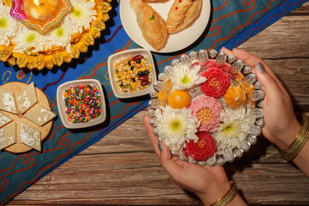 Hands holding a plate of traditional floral sweets