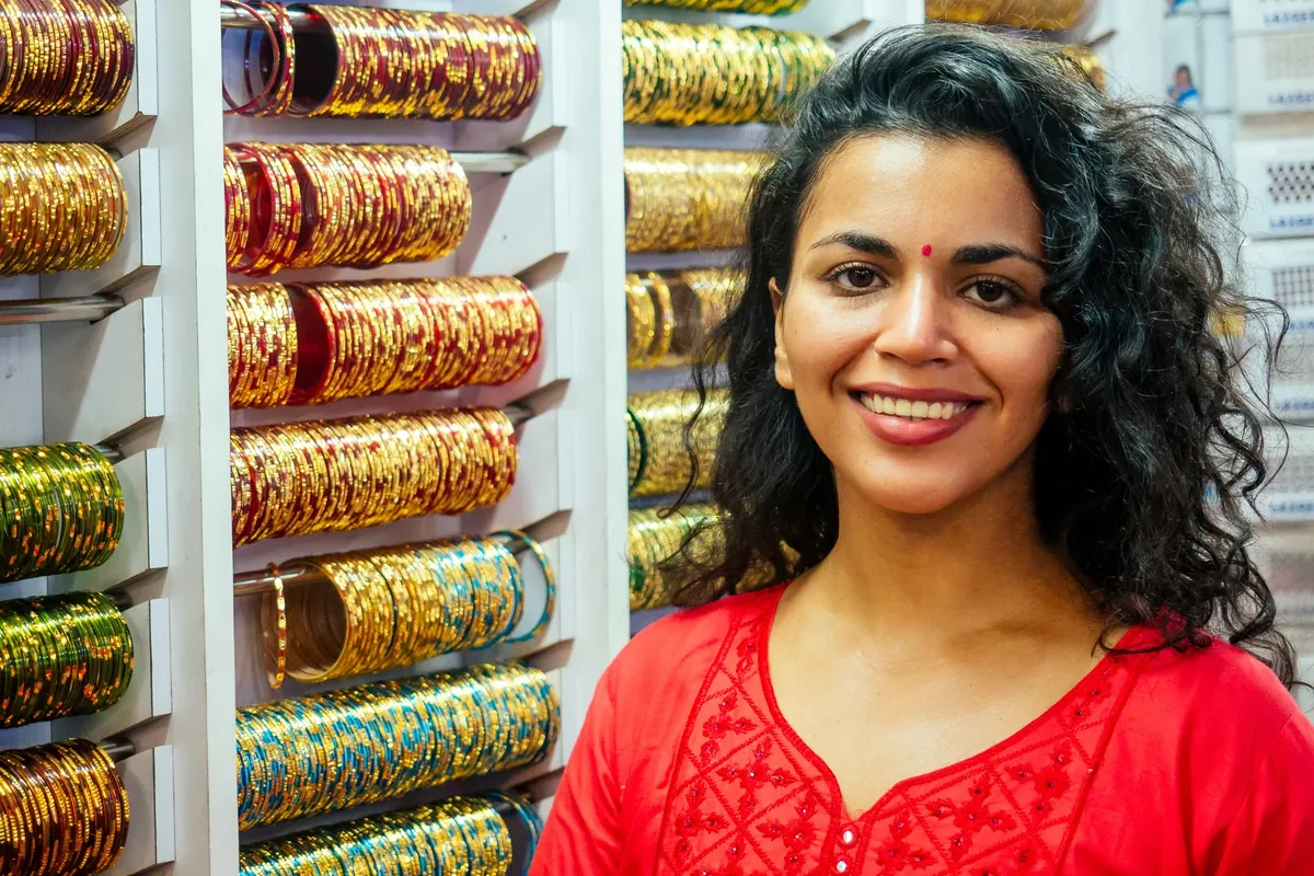 A smiling woman standing in front of shelves of bangles in a jewellery shop
