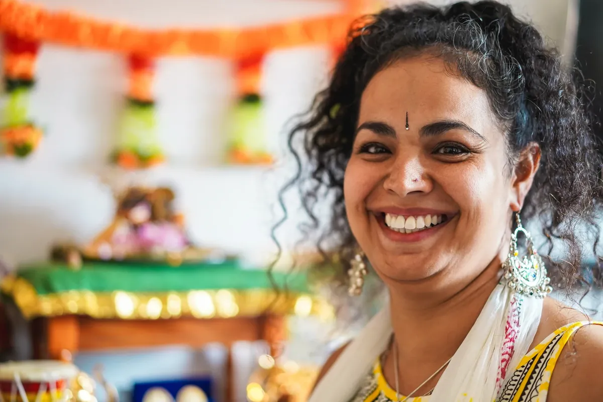 A smiling woman wearing large silver-toned jhumka earrings